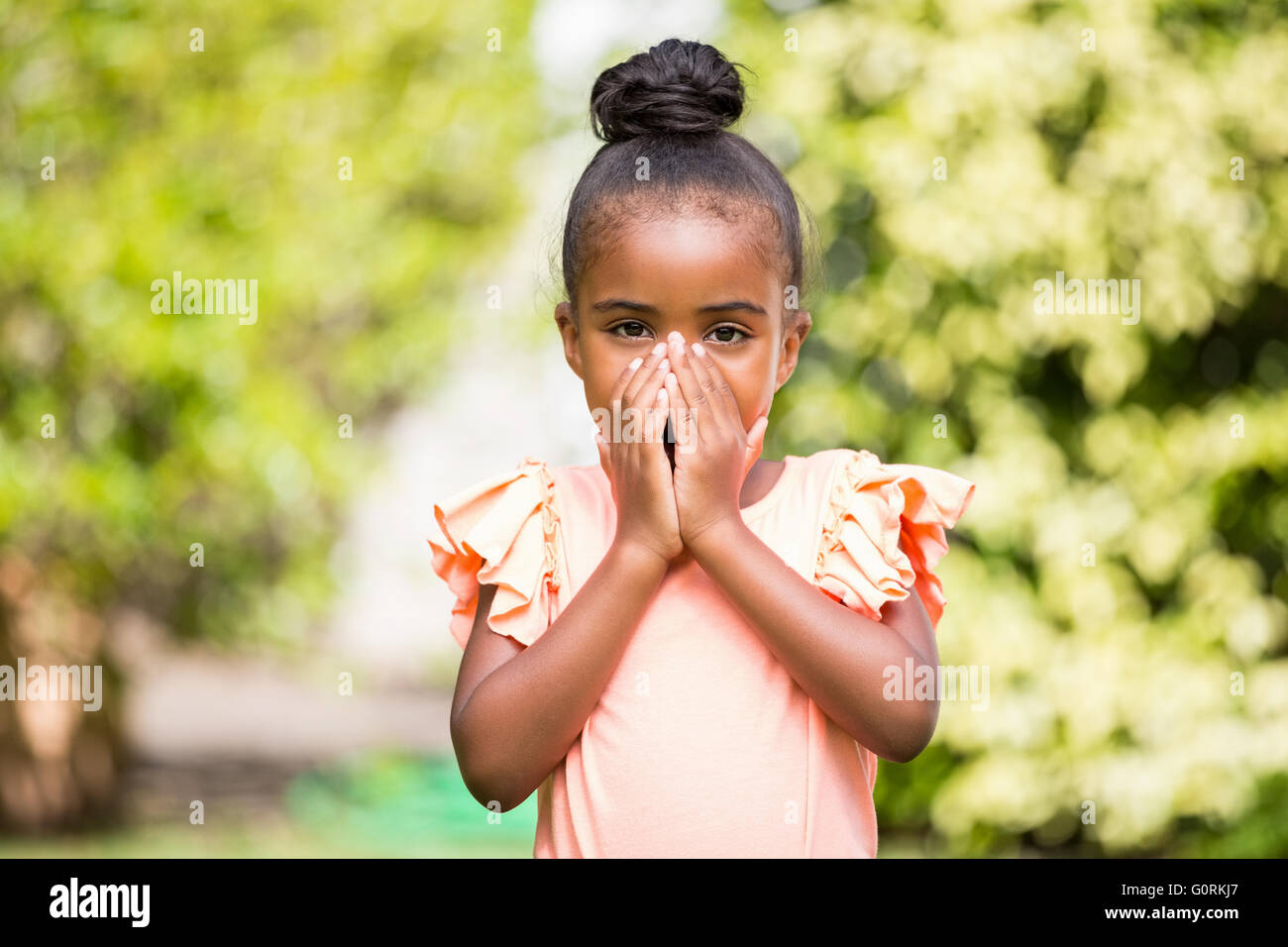 Kleines Mädchen versteckt den Mund im park Stockfoto