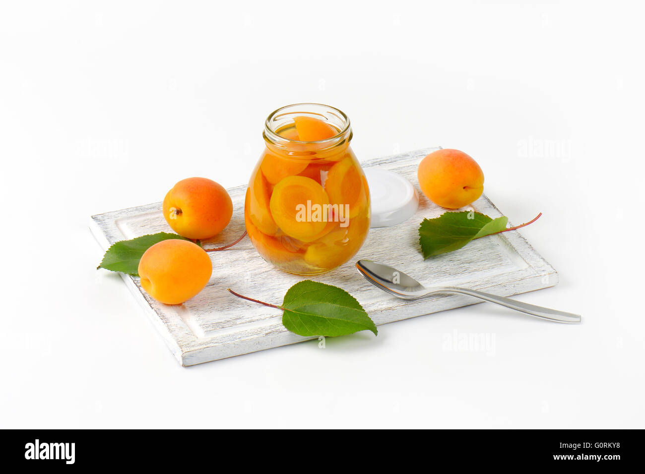 Glas mit Aprikosen-Kompott und Schüssel mit frischen Aprikosen Stockfoto