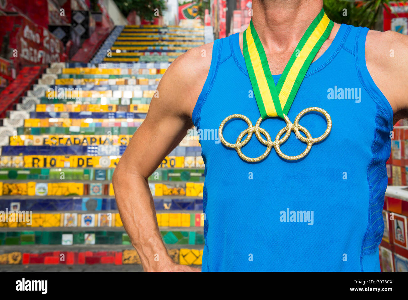 RIO DE JANEIRO - 29. März 2016: Athlet mit Goldmedaille Olympische Ringe steht im Freien vor der berühmten Selaron-Treppe. Stockfoto
