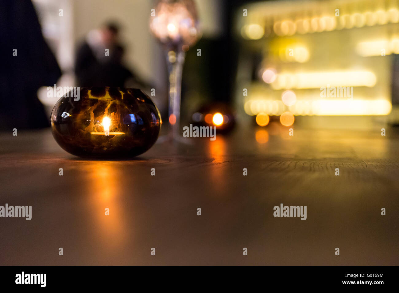 Eine Kerze leuchtet in einem runden Glas auf einem Holztisch. Stockfoto