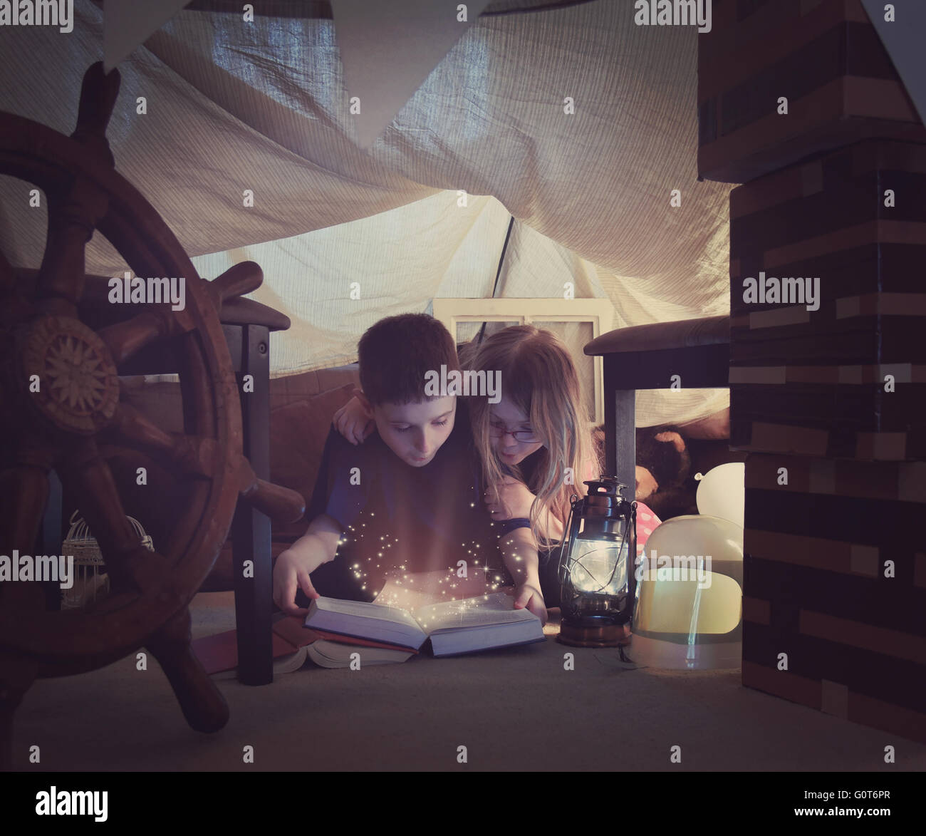 Zwei kleine Kinder lesen ein Buch zusammen mit funkelt in einem Zelt Fort zu Hause für eine Storytime oder Lernkonzept. Stockfoto
