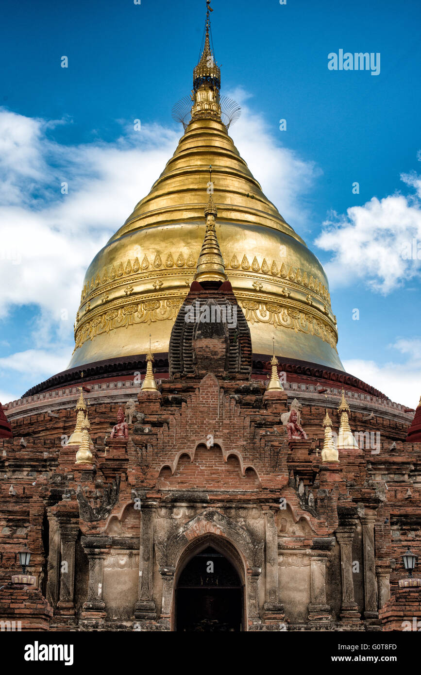 Dhammayazika Pagoda Bagan Myanmar // [Dhammayazika Pagoda] BAGAN, MYANMAR-die Dhammayazika Pagoda (auch Dhamma-ya-ka Zedi) ist ein buddhistischer Tempel im Dorf Pwasaw im südlichen Teil der Bagan-Ebene in Myanmar. Sie wurde 1196 während der Regierungszeit von König Narapatisithu erbaut. Die Pagode ist kreisförmig gestaltet und besteht aus Ziegeln. Die drei Terrassen enthalten Terrakotta-Fliesen, die Szenen aus dem Jataka illustrieren, und es ist heute mit einer großen goldenen Schirmkuppel umgebaut. Stockfoto