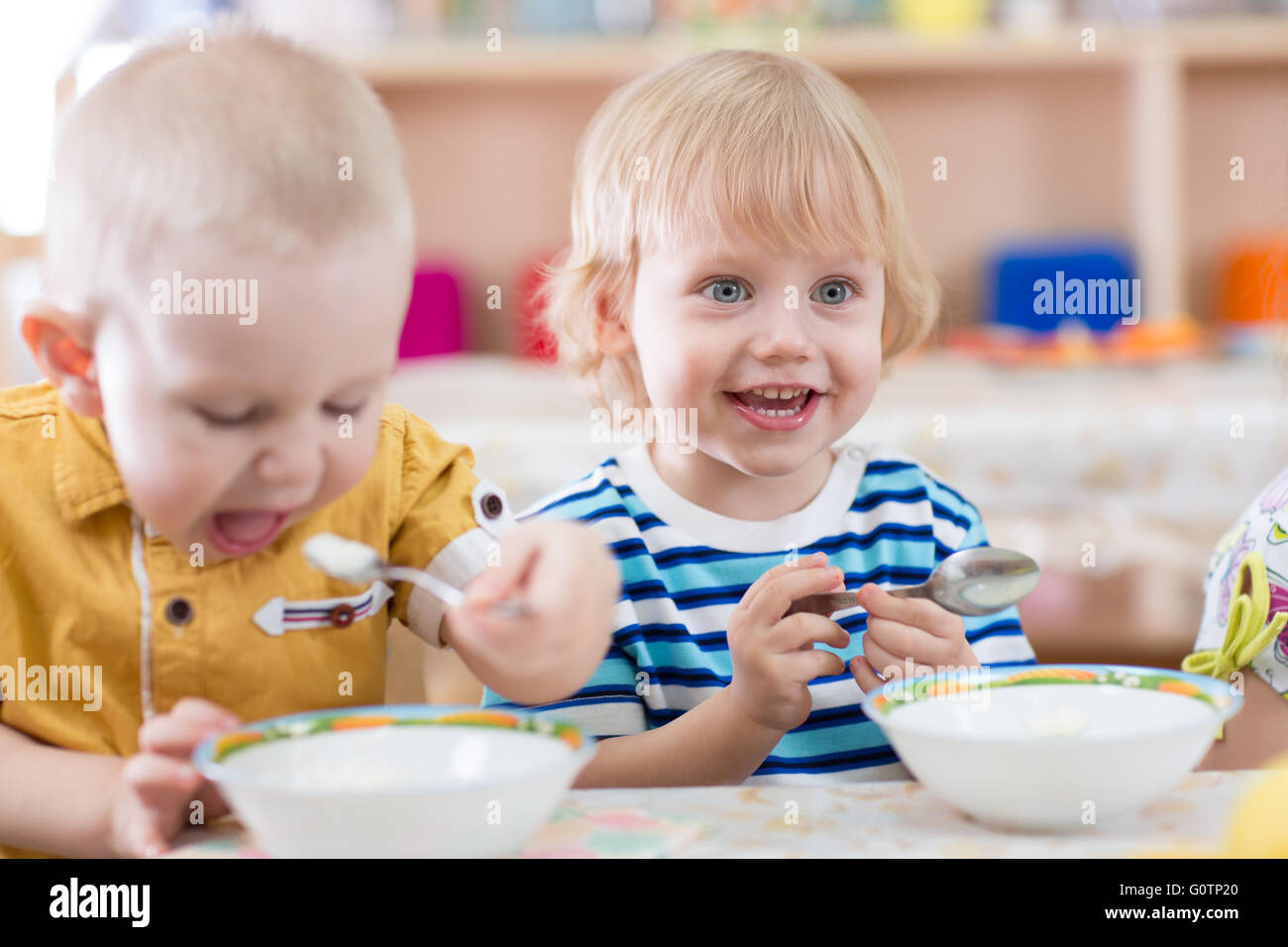 Lustiges kleines Kind im Kindergarten Essen Lächeln Stockfoto