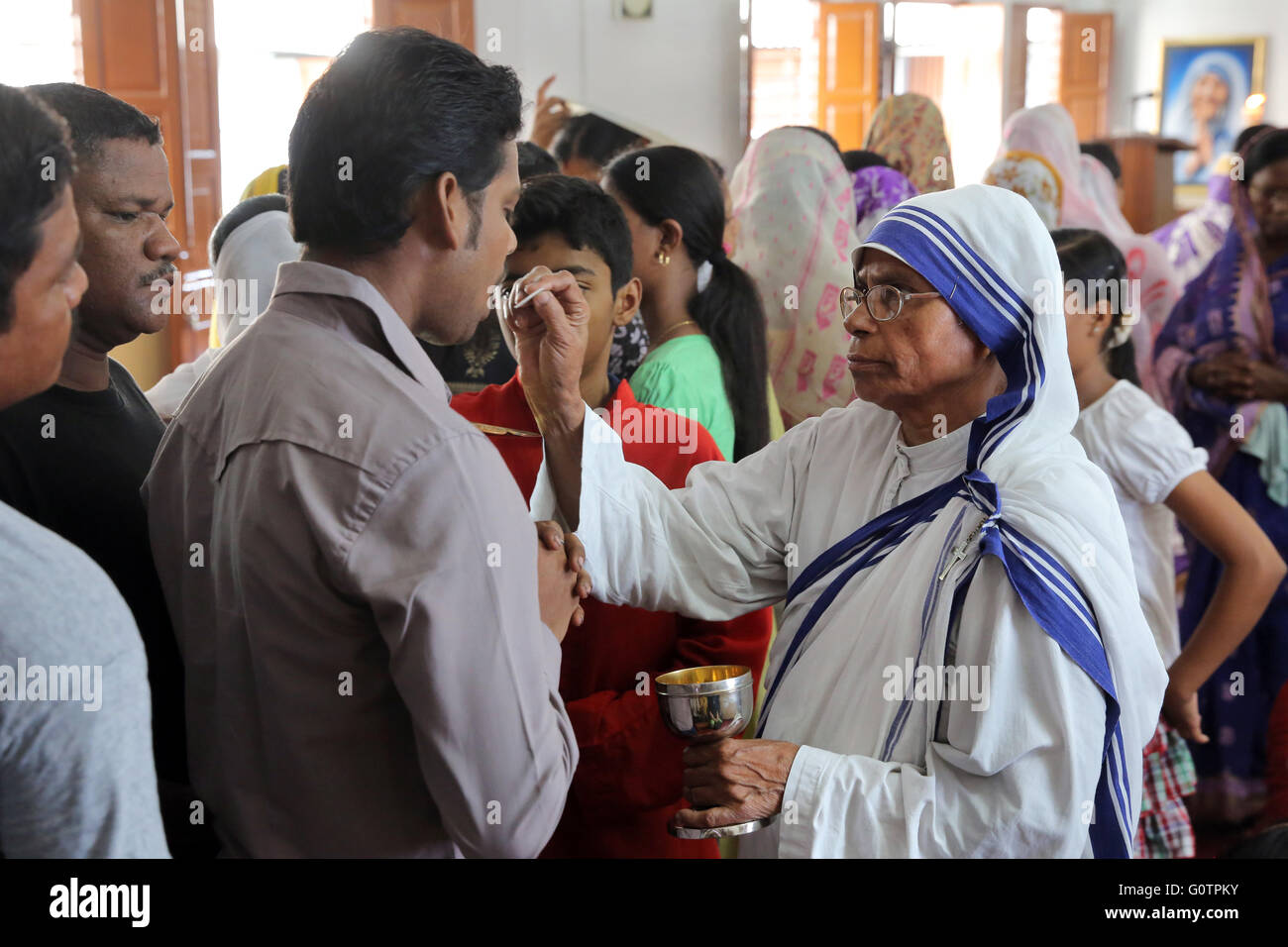 Schwester Teresa (Missionarinnen der Nächstenliebe) teilt die Eucharistie während einer katholischen Sonntagsmesse in einer kleinen Kirche in Kalkutta, Indien Stockfoto