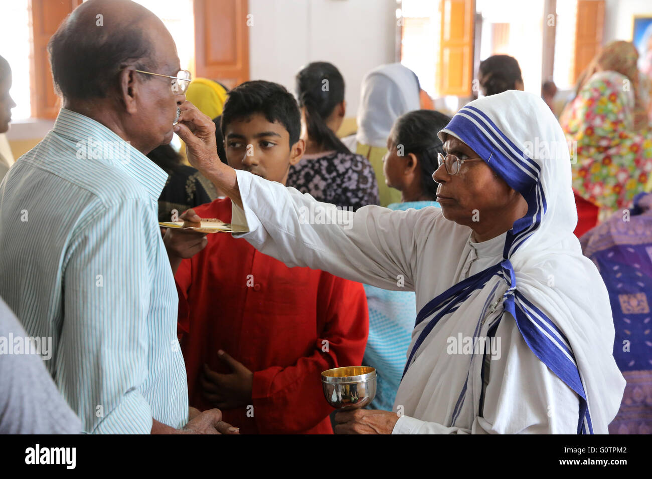 Schwester Teresa (Missionarinnen der Nächstenliebe) teilt die Eucharistie während einer katholischen Sonntagsmesse in einer kleinen Kirche in Kalkutta, Indien Stockfoto