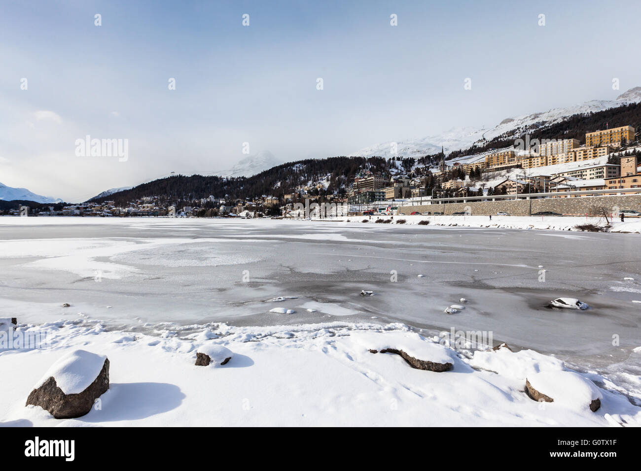 Blick auf den eisigen Sankt Moritzer See und die Stadt auf dem Berg im Winter, Graubünden, Schweiz Stockfoto