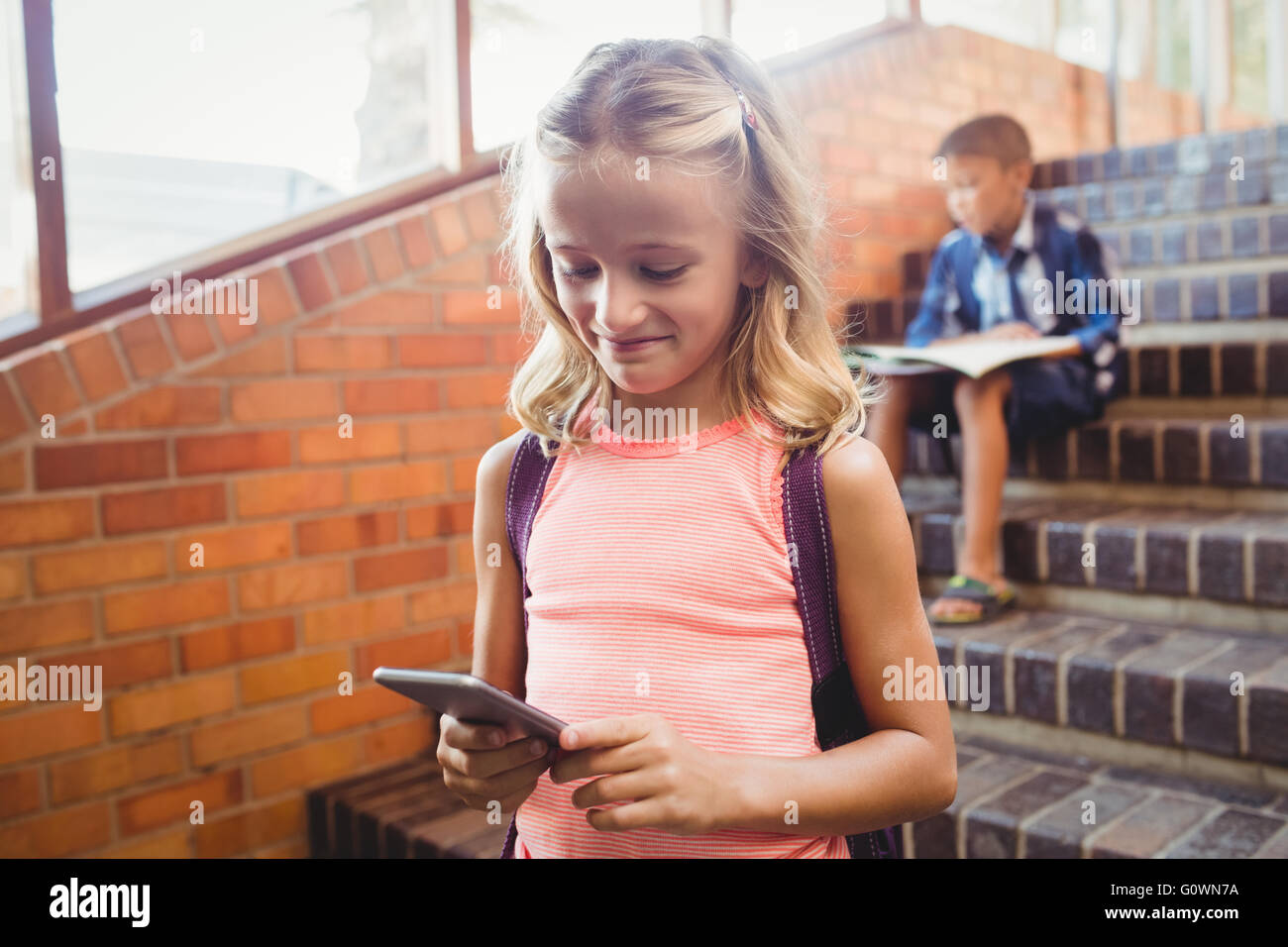 Niedliche kleine Schulmädchen Blick auf ihr smartphone Stockfoto