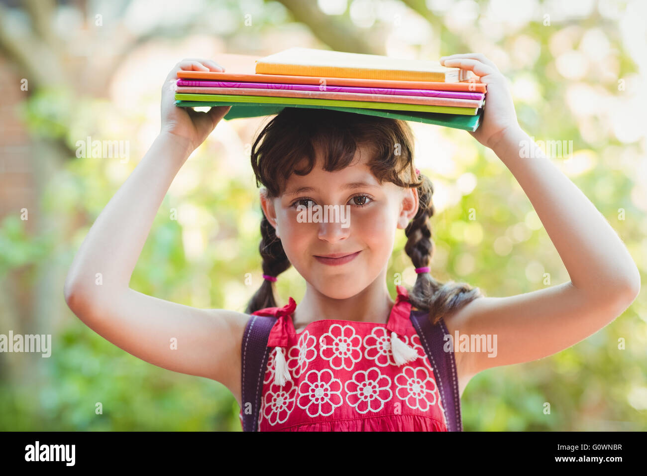 Brünette Mädchen mit Büchern über ihre Köpfe Stockfoto