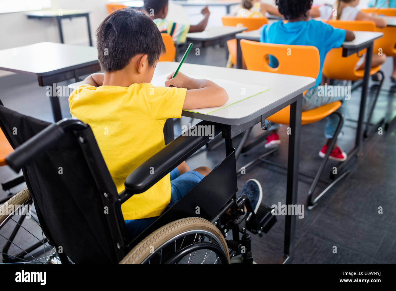 Ein Schüler im Rollstuhl an seinem Schreibtisch arbeiten Stockfoto