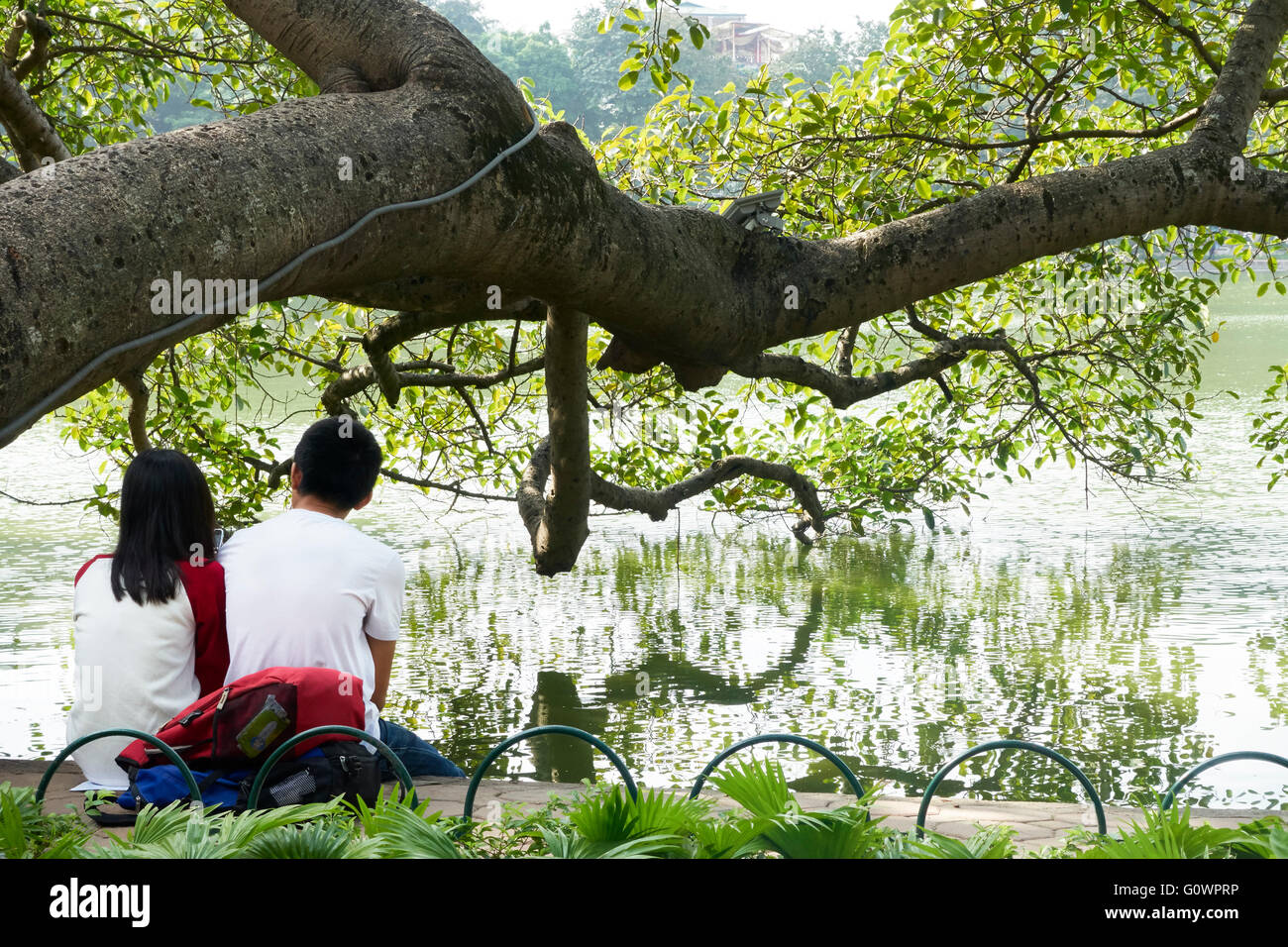 Ein Junge und ein Mädchen sitzen am Ufer des Hoan-Kiem-See, Hanoi, Vietnam Stockfoto