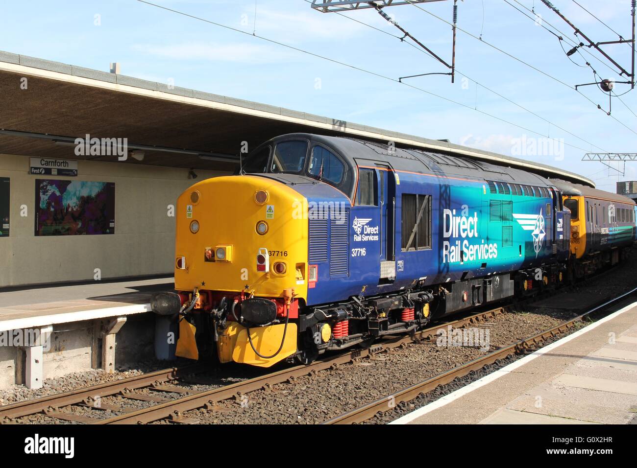 Klasse 37 Diesel Lokomotive 37716 Direct Rail Services Livree auf Gleis 2 am Bahnhof von Carnforth hinter DVT 9705 Stockfoto