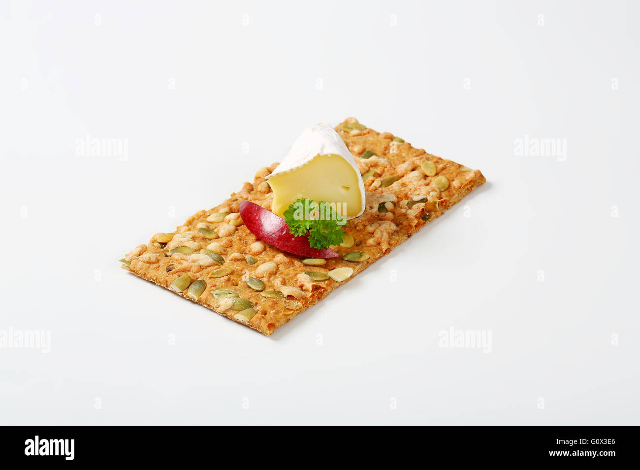 Kürbiskern-Cracker mit weißen Rinde Käse und Apfelscheibe auf weißem Hintergrund Stockfoto