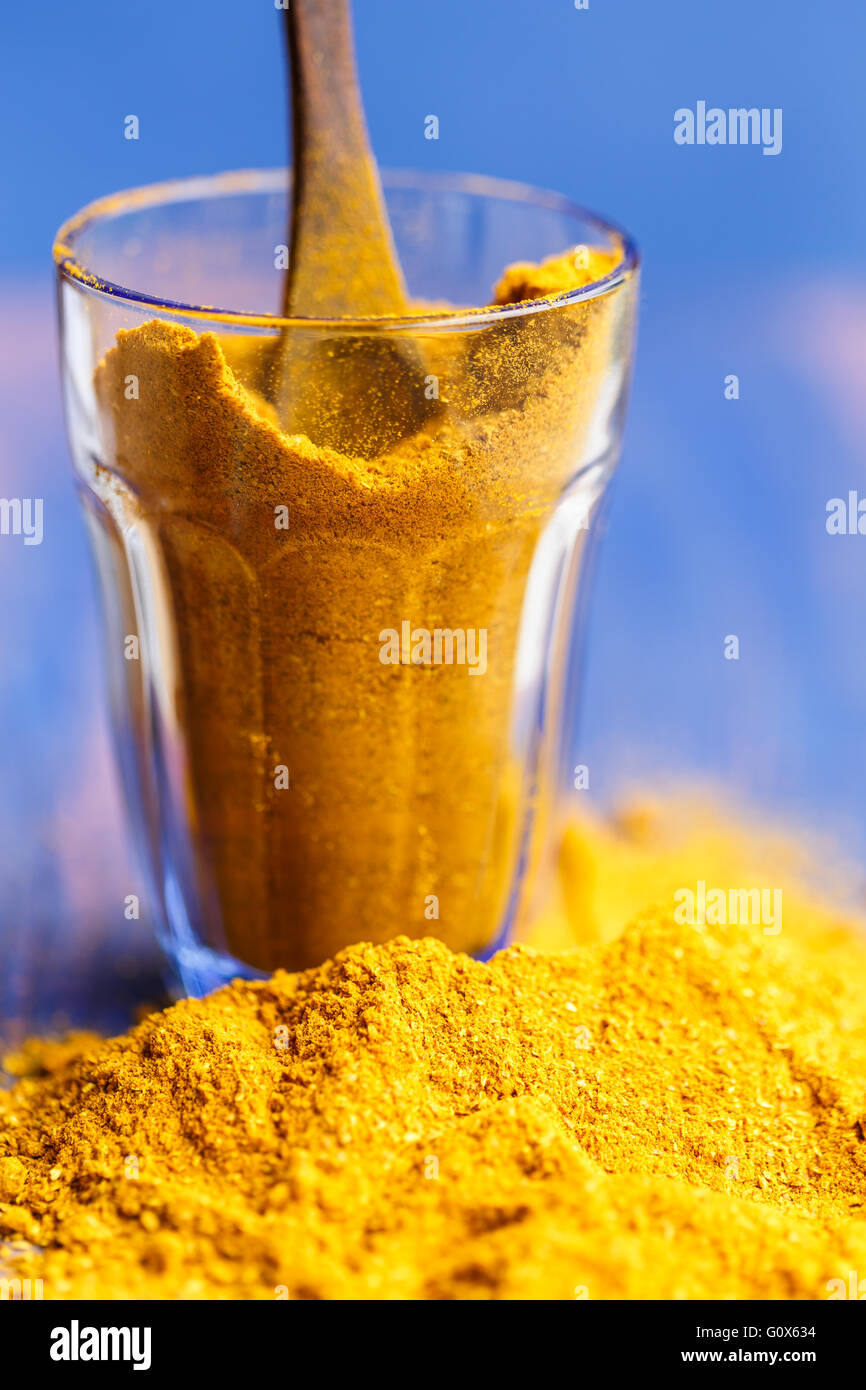 Curry-Pulver in ein Glas vor blauem Hintergrund Stockfoto