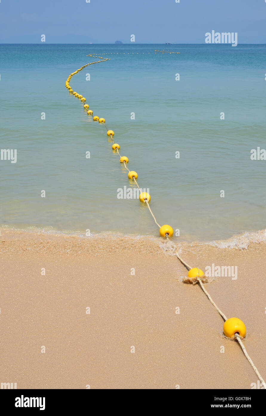 Kette von gelben Polystyrol Meer Marker Bojen mit Kabel-Schlepp am Sandstrand und im blauen Meerwasser mit klaren Himmel über perspectiv Stockfoto