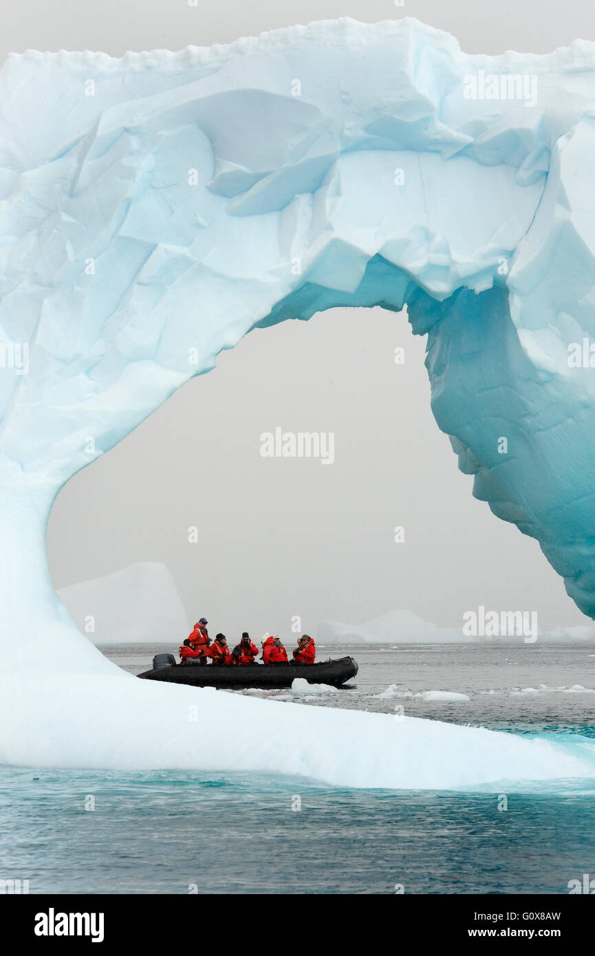 Tierkreis mit Touristen hinter Eisberg Bogen, antarktische Halbinsel Stockfoto