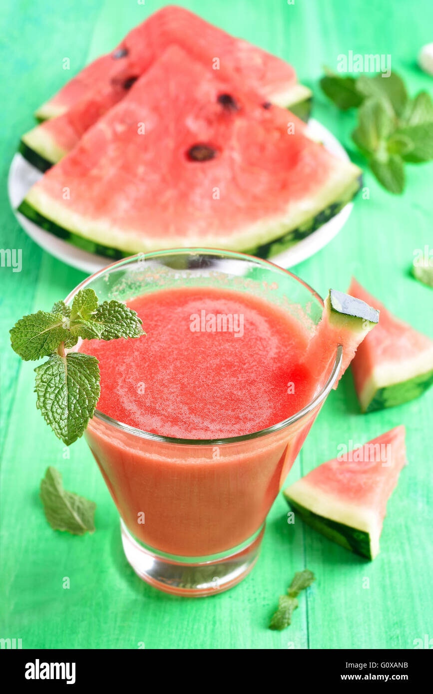 Wassermelone Saft Smoothie in Glas und Scheiben auf grünem Hintergrund aus Holz Stockfoto