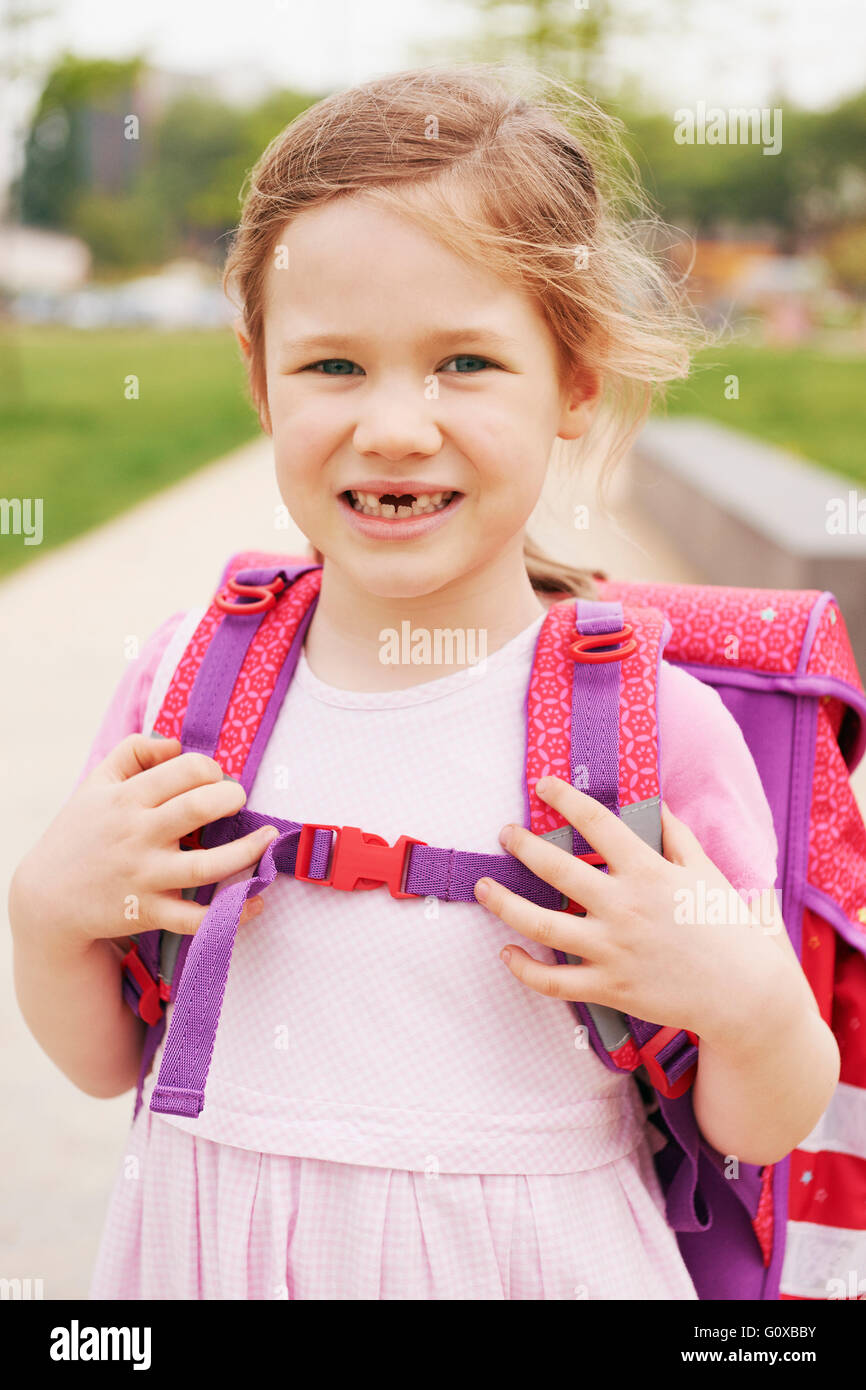 Porträt von 5 jährige Schülerin mit rosa und lila Schultasche, lächelnd und Blick in die Kamera zeigen ihre vorderen Zähne fehlen Stockfoto