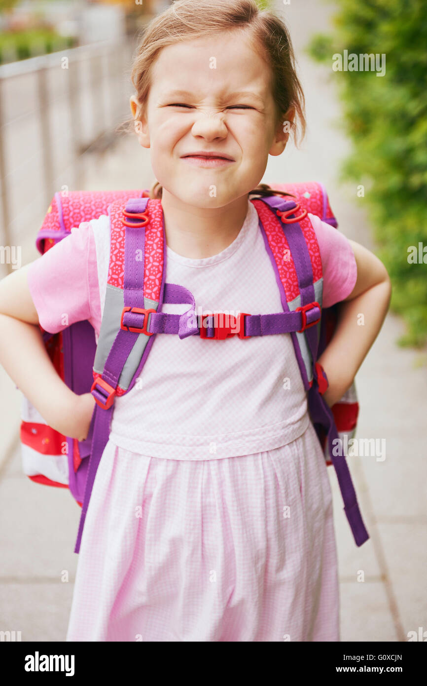 5 Jahre alte Schülerin mit rosa Schulranzen Grimassen mit Händen auf den Hüften Stockfoto