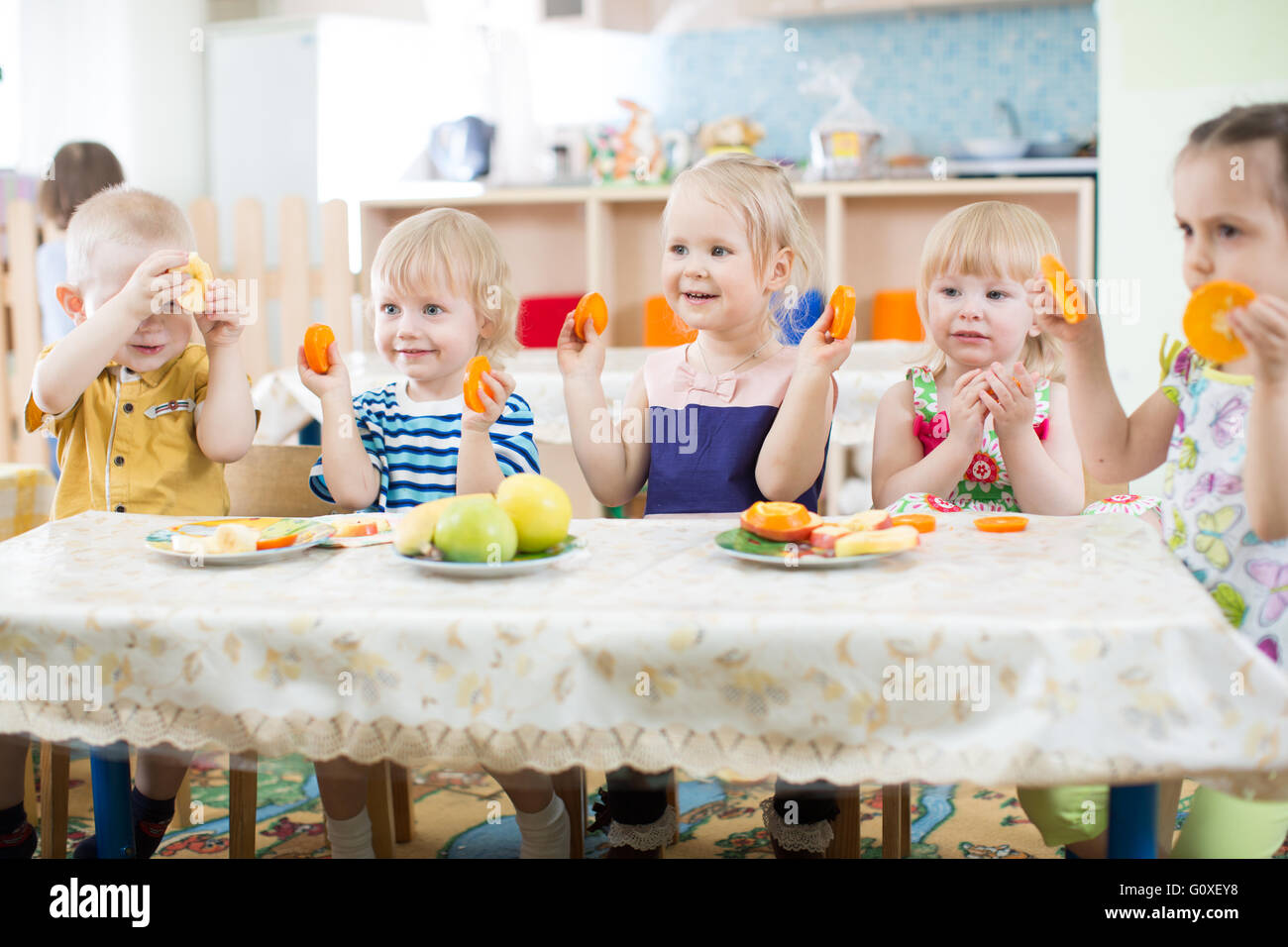 Lustige Kinder essen Obst im Kindergarten oder in der Kindertagesstätte Stockfoto