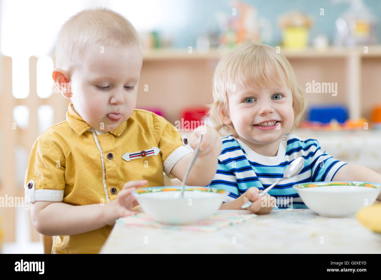 Zwei lustige lächelnden kleinen Kinder Essen im kindergarten Stockfoto
