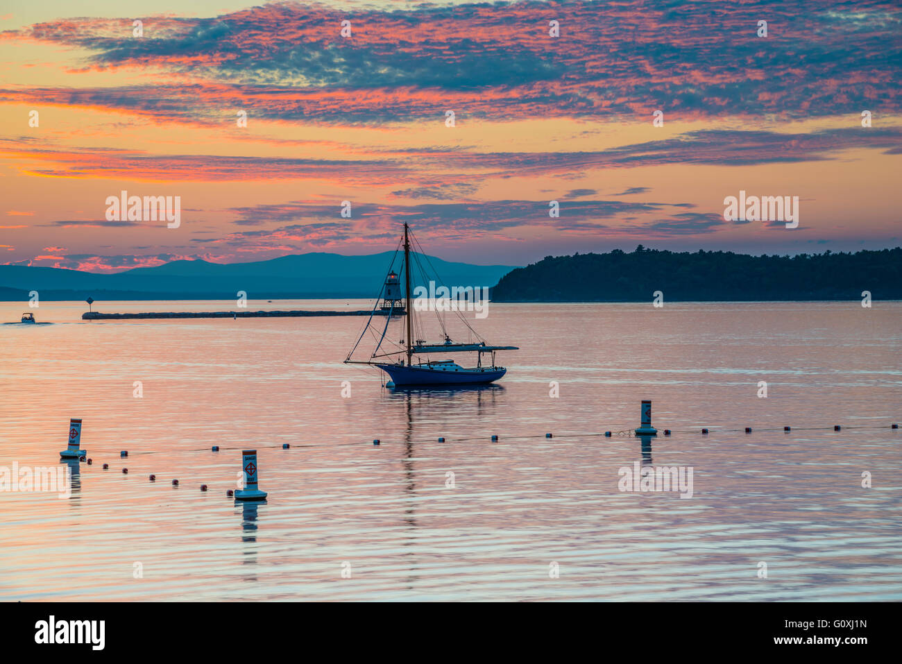 Sonnenuntergang Bild Segelboot und Leuchtturm am Lake Champlain mit Bergen im Hintergrund genommen in Burlington, Vermont. Stockfoto