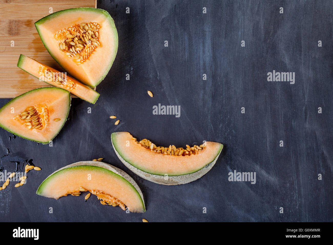 Scheiben Melone auf Schneidebrett am schwarzen Brett Stockfoto