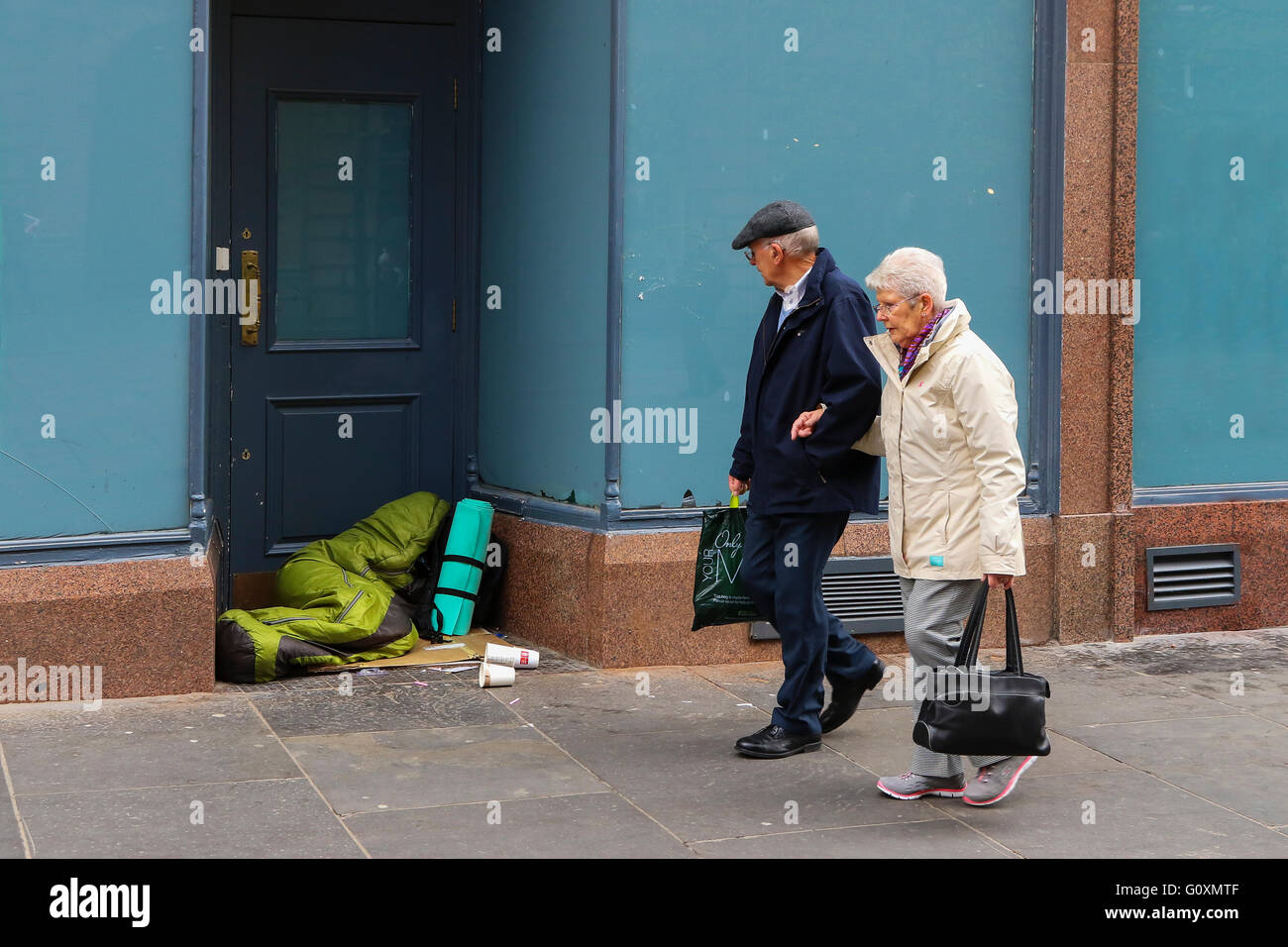 Mann und Frau zu Fuß vorbei an jemand schlafen rau in einem Shop Eingang, Glasgow, Stadt, Schottland, Vereinigtes Königreich Stockfoto