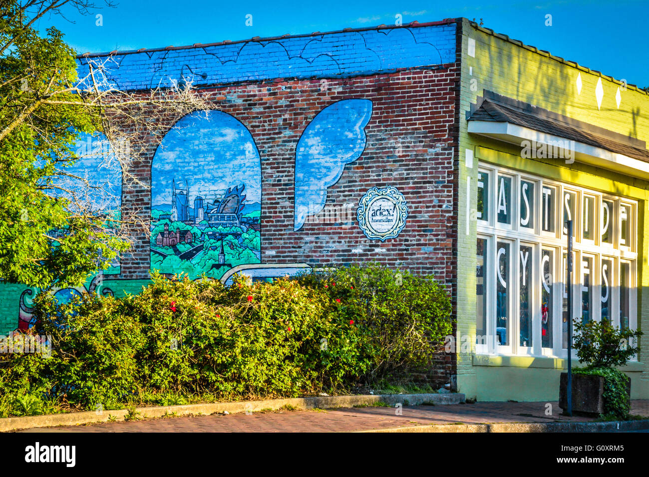 Künstlerische und bunte Wandgemälde an Eastside Cycles Backsteinbau bei Sonnenuntergang im Szeneviertel Five Points in hip East Nashville, TN Stockfoto