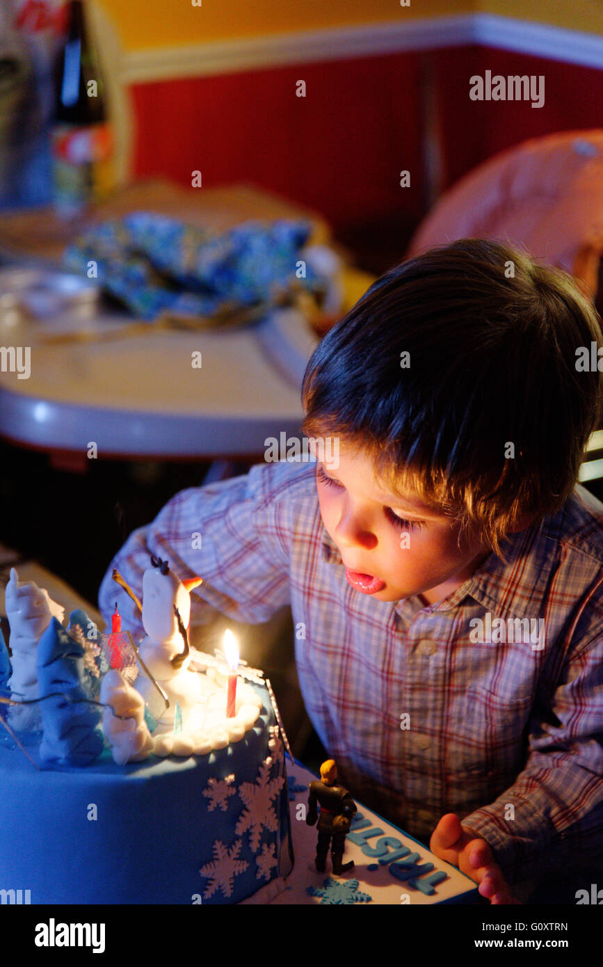 Ein kleiner Junge (4 Jahre alt) Ausblasen der Kerzen auf seine Geburtstagstorte Stockfoto