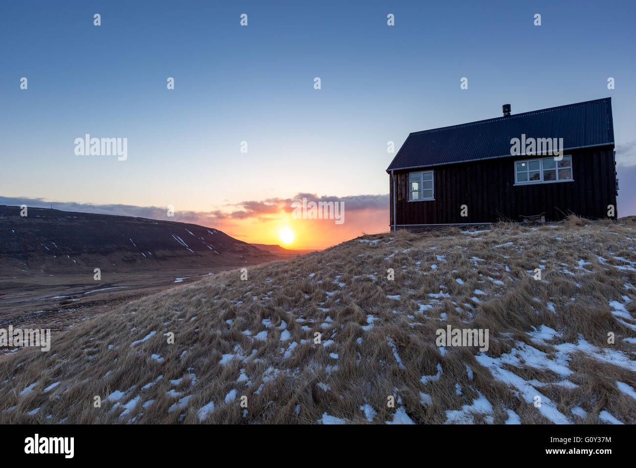 Sonnenuntergang von einem schwarzen isländischen Häuschen in Westisland Stockfoto