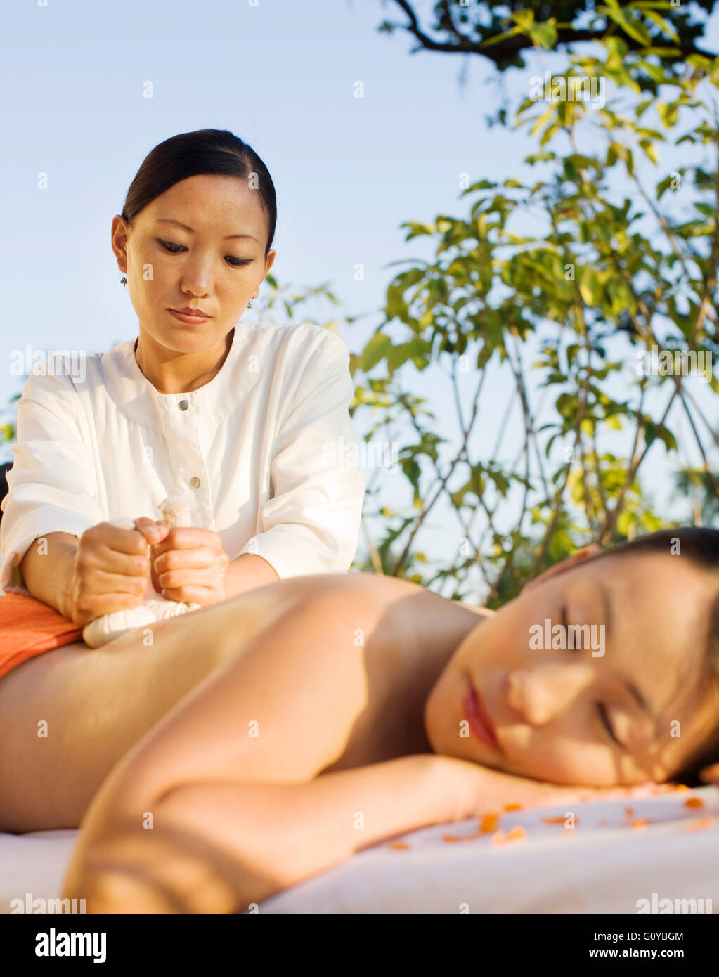 Eine Frau erhält eine Thai Herbal Ball Massage im Ananada im Himalaya. Uttarakhand, Indien. Stockfoto