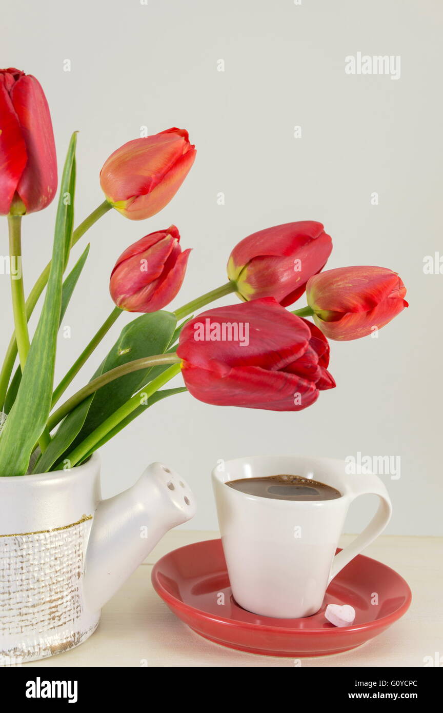 Rote Tulpen mit einer Tasse Kaffee auf einem Holztisch Stockfoto