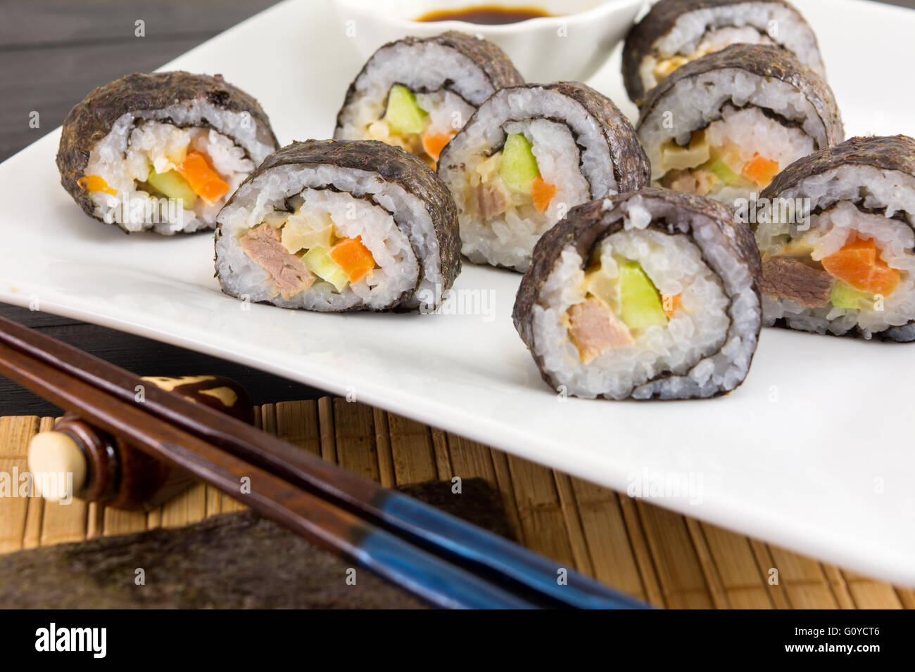 Sushi-Rollen mit hölzernen Stäbchen serviert Stockfoto