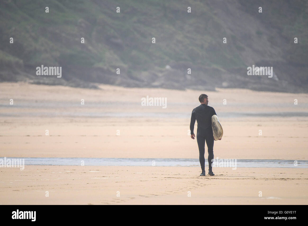 Eine einsame Surfer geht Fistral Strand entlang. Stockfoto