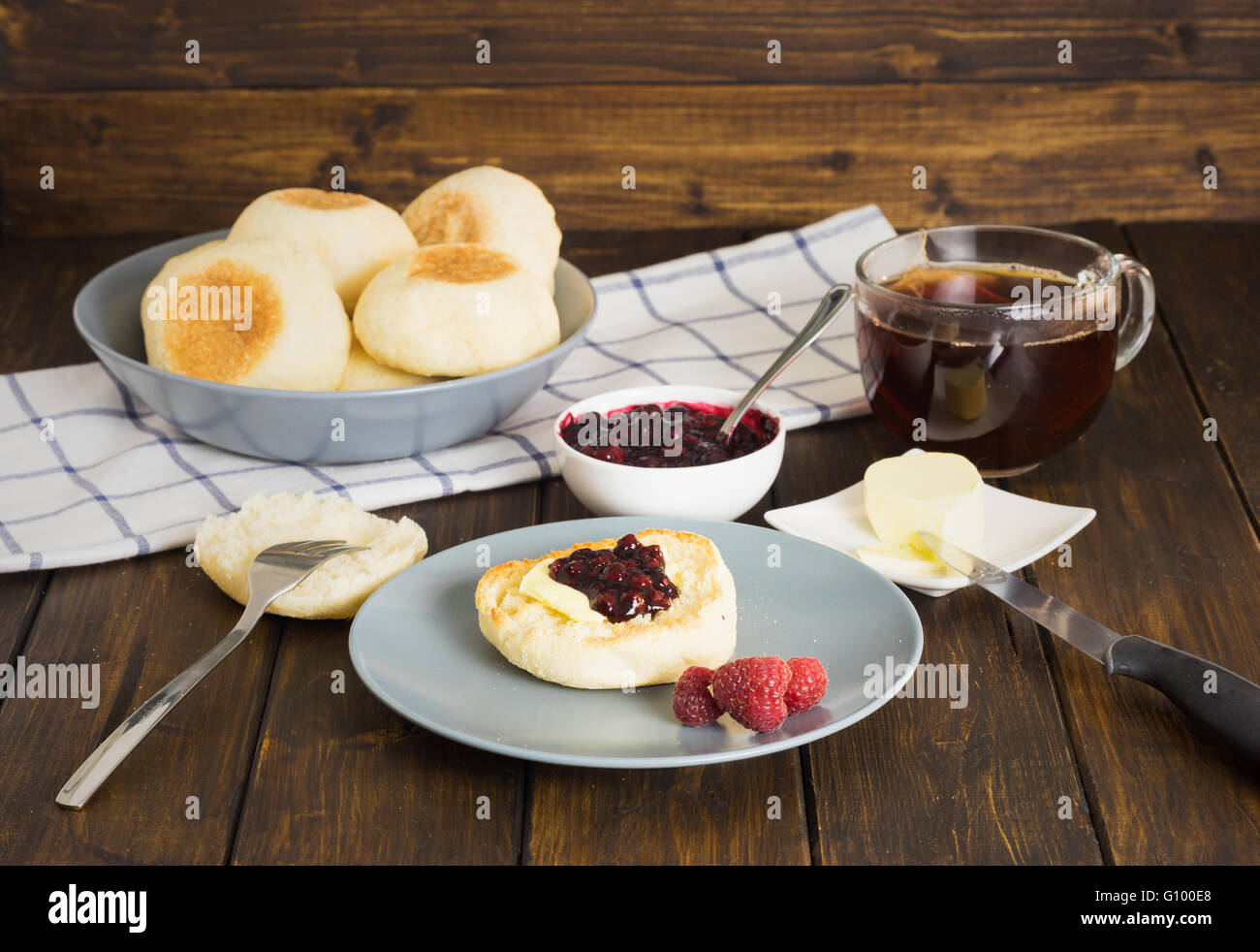 Englische Muffins mit Marmelade und Butter auf hölzernen Hintergrund im rustikalen Stil Stockfoto