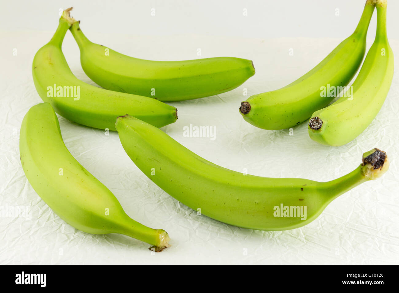 Grünen jungen Bananen auf weißen Textilien Stockfoto