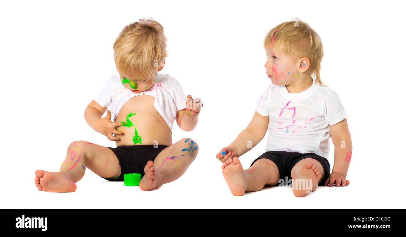 Zwillinge-Brüder spielen mit Farbe, isoliert auf weiss. Stockfoto