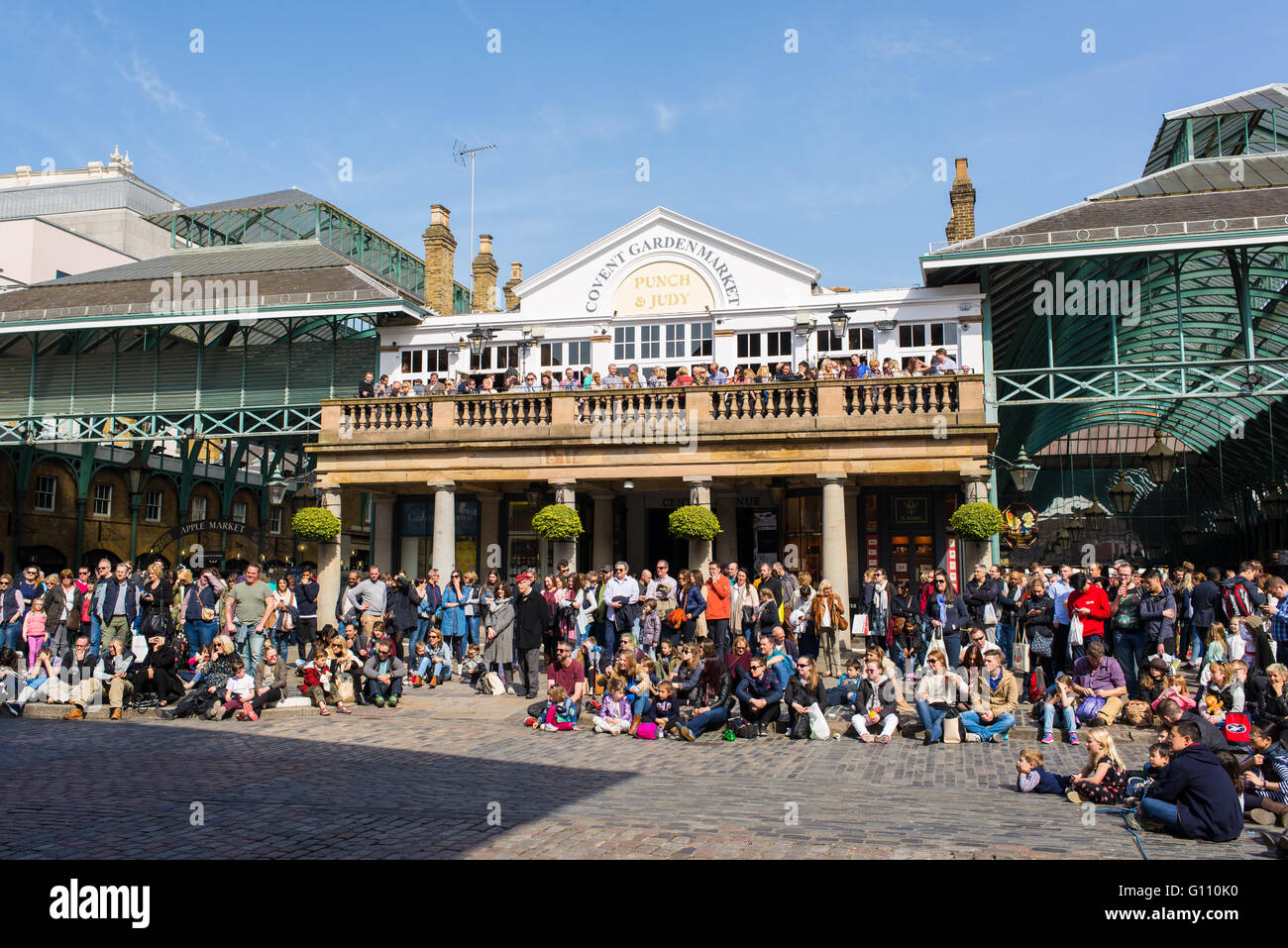 Touristen, die gerade ein Straßenmusikant auf dem Vorplatz der Covent Garden Market zeigen Stockfoto