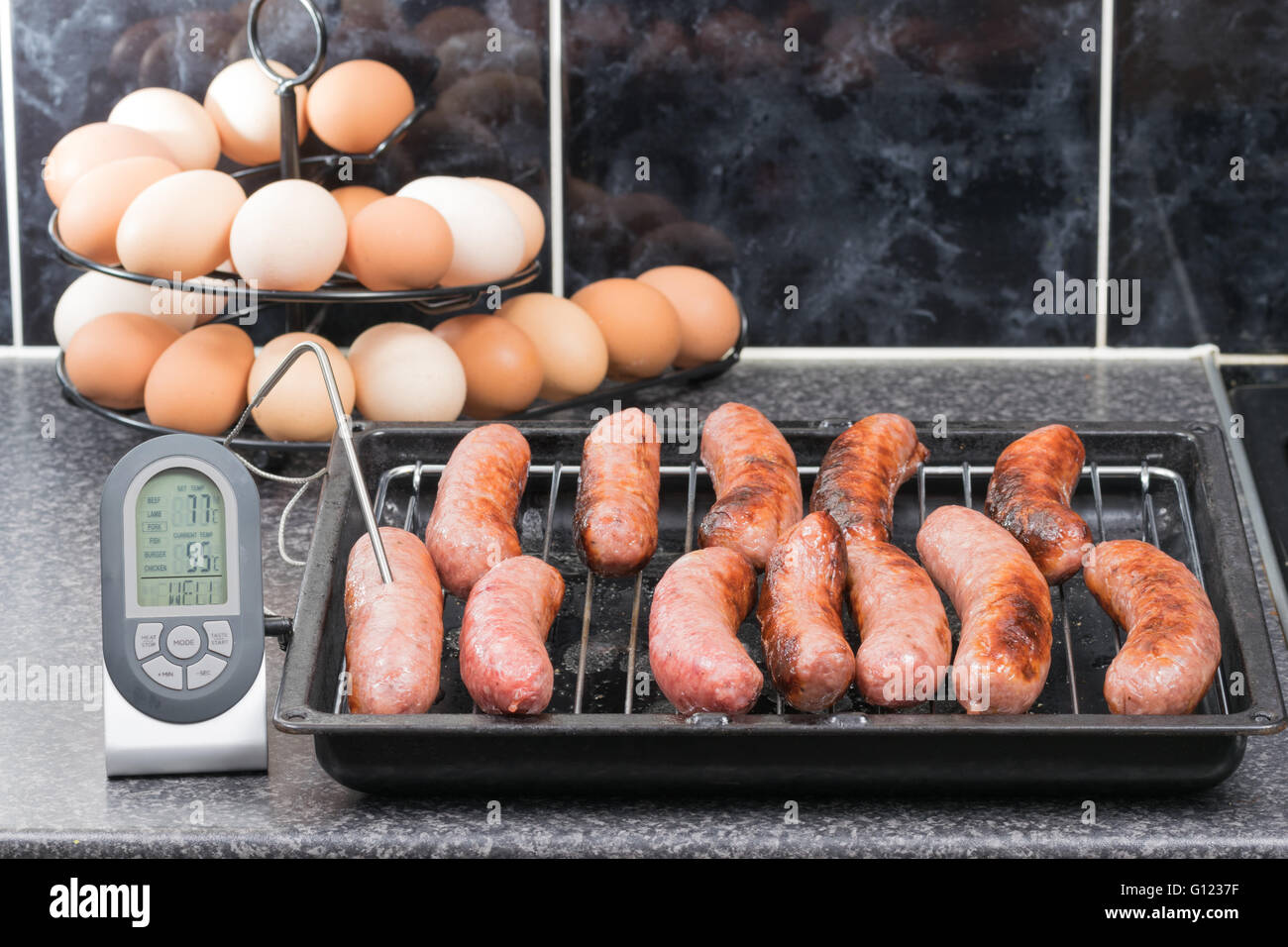 Überprüfen die Gartemperatur von gegrillten Würstchen mit ein digitales Fleischthermometer Stockfoto
