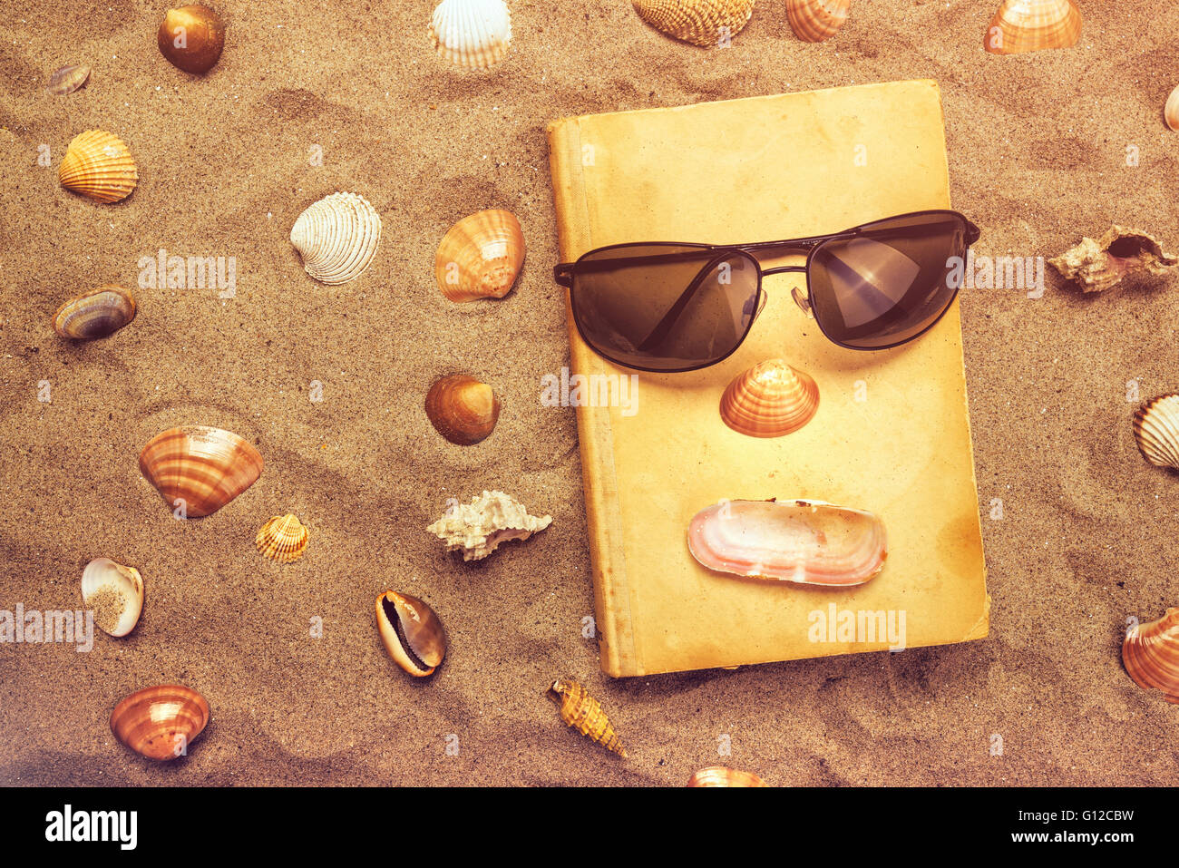 Lesen Sie alte Lieblingsbuch im Sommer Urlaub Strandurlaub, Draufsicht eines Buches und Sonnenbrillen in warmen Strand Schnee. Stockfoto