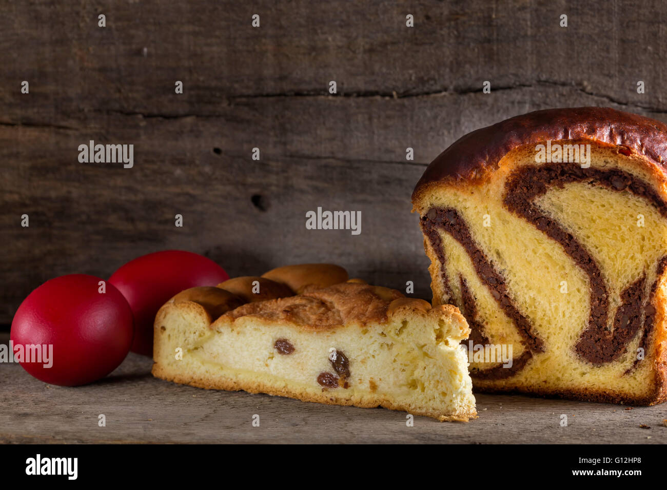 Rumänische Kuchen Cozonac mit zertrümmerten Nüssen und Pasca mit Käse und Rosinen und traditionelle farbige Ostereier Stockfoto