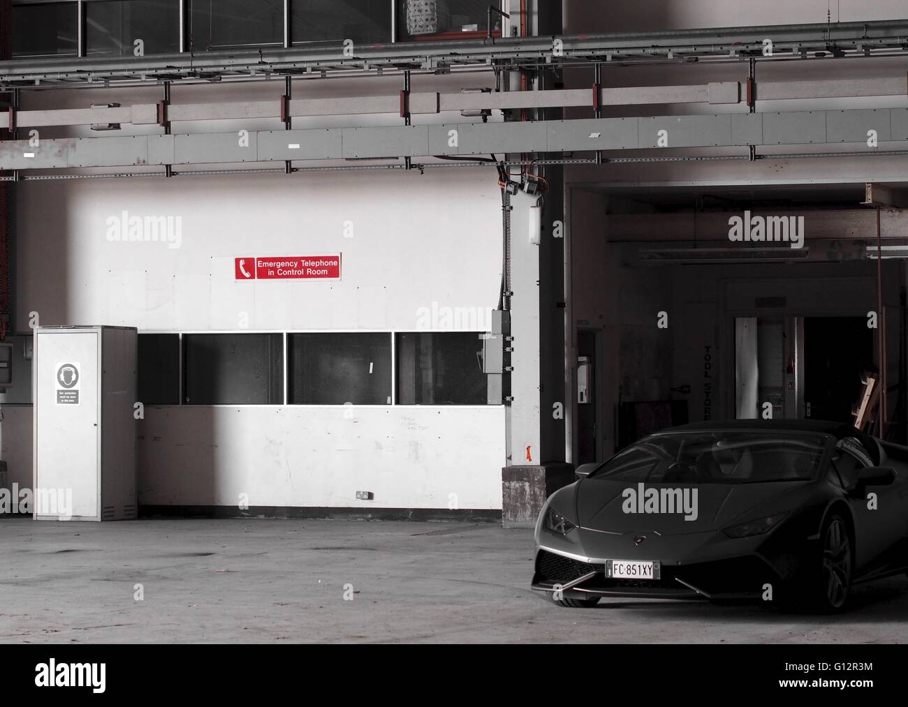Lamborghini Huracan in Lager mit Schild an Wand sagen Notfall Telefon im Kontrollraum Stockfoto