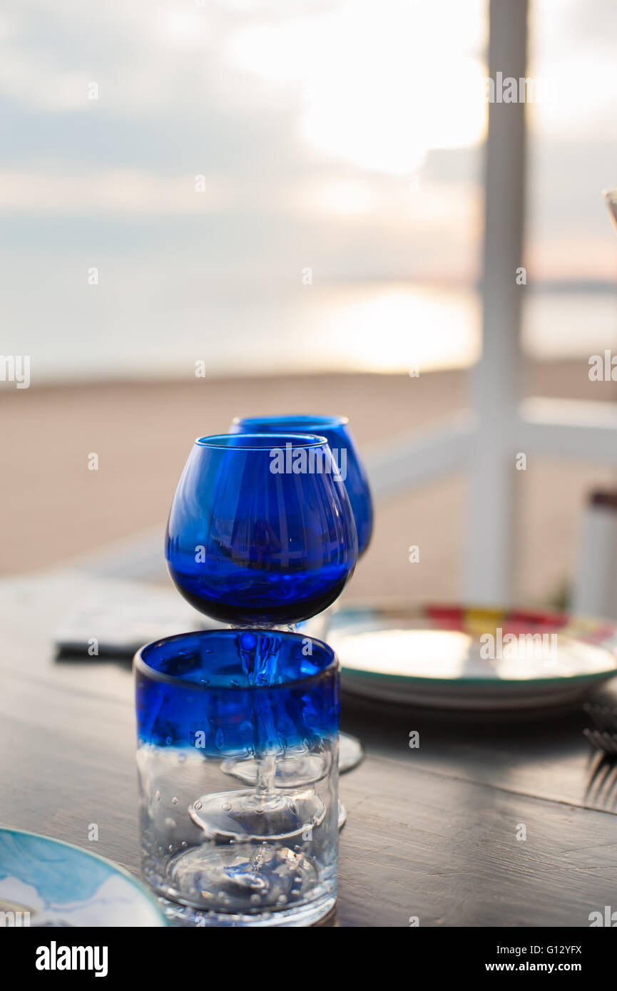 Blauglas Closeup an Tischkonzept der Liebe mit romantischen Sonnenuntergang am Strand im Hintergrund Stockfoto