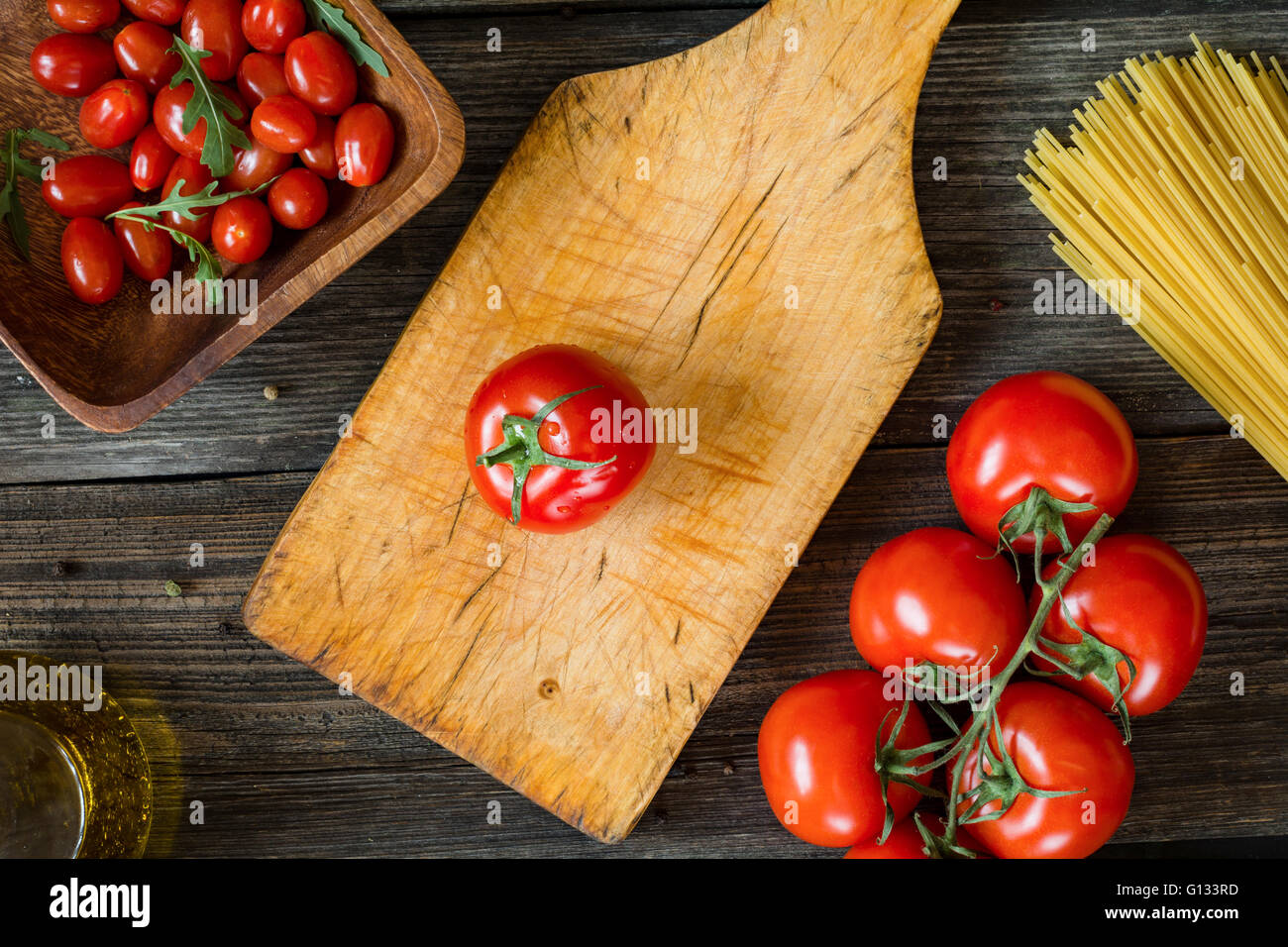 Draufsicht Speisen der italienischen Küche Zutaten auf rustikalen hölzernen Hintergrund. Spaghetti Nudeln, Olivenöl, Tomaten und Rucola-Salat Stockfoto