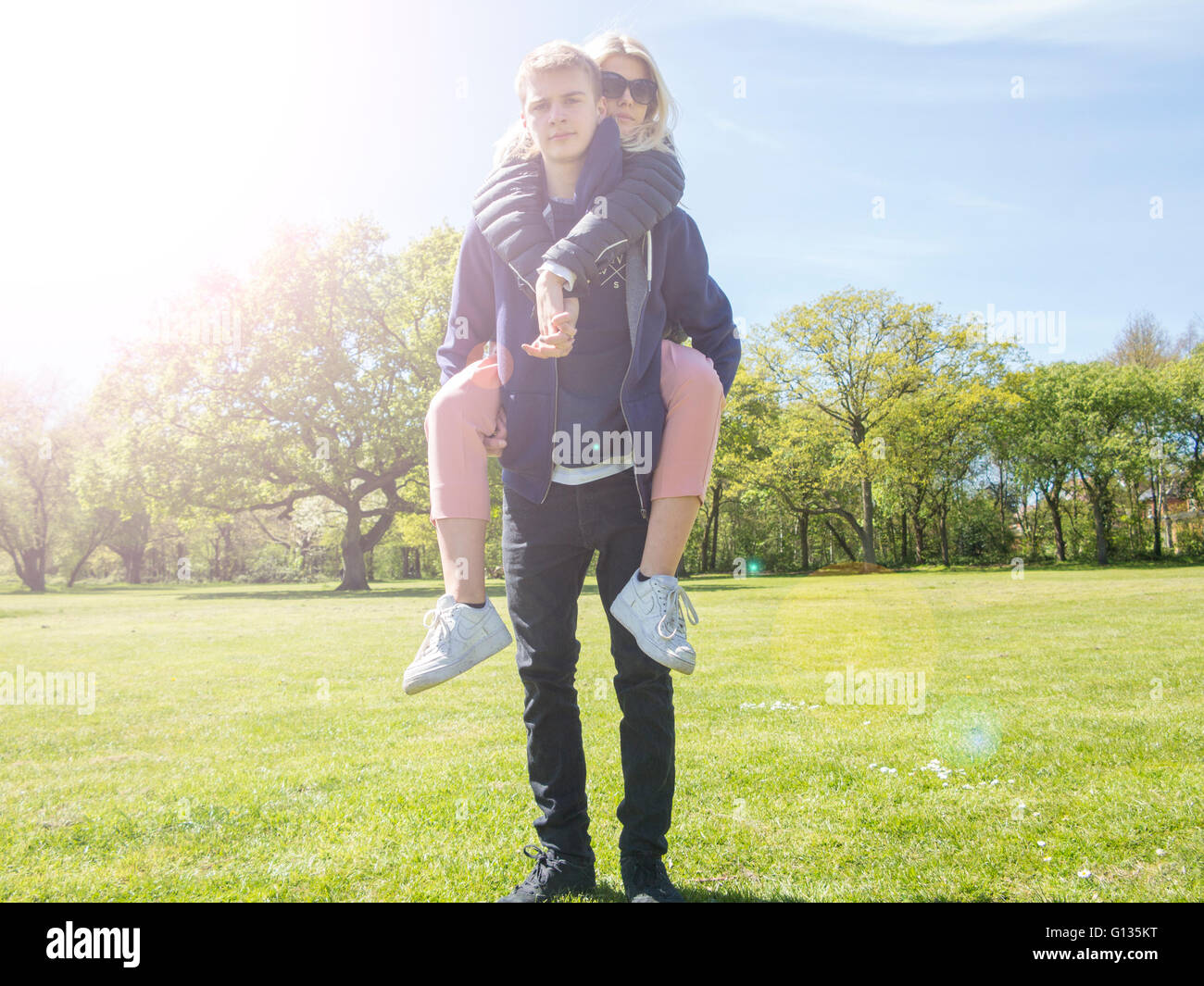 Ein Junge gibt einer Mädchen eine Huckepack in den Sommer Stockfoto