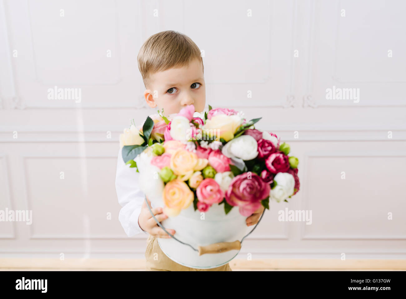 Junge hält einen Eimer mit Blumen Stockfoto