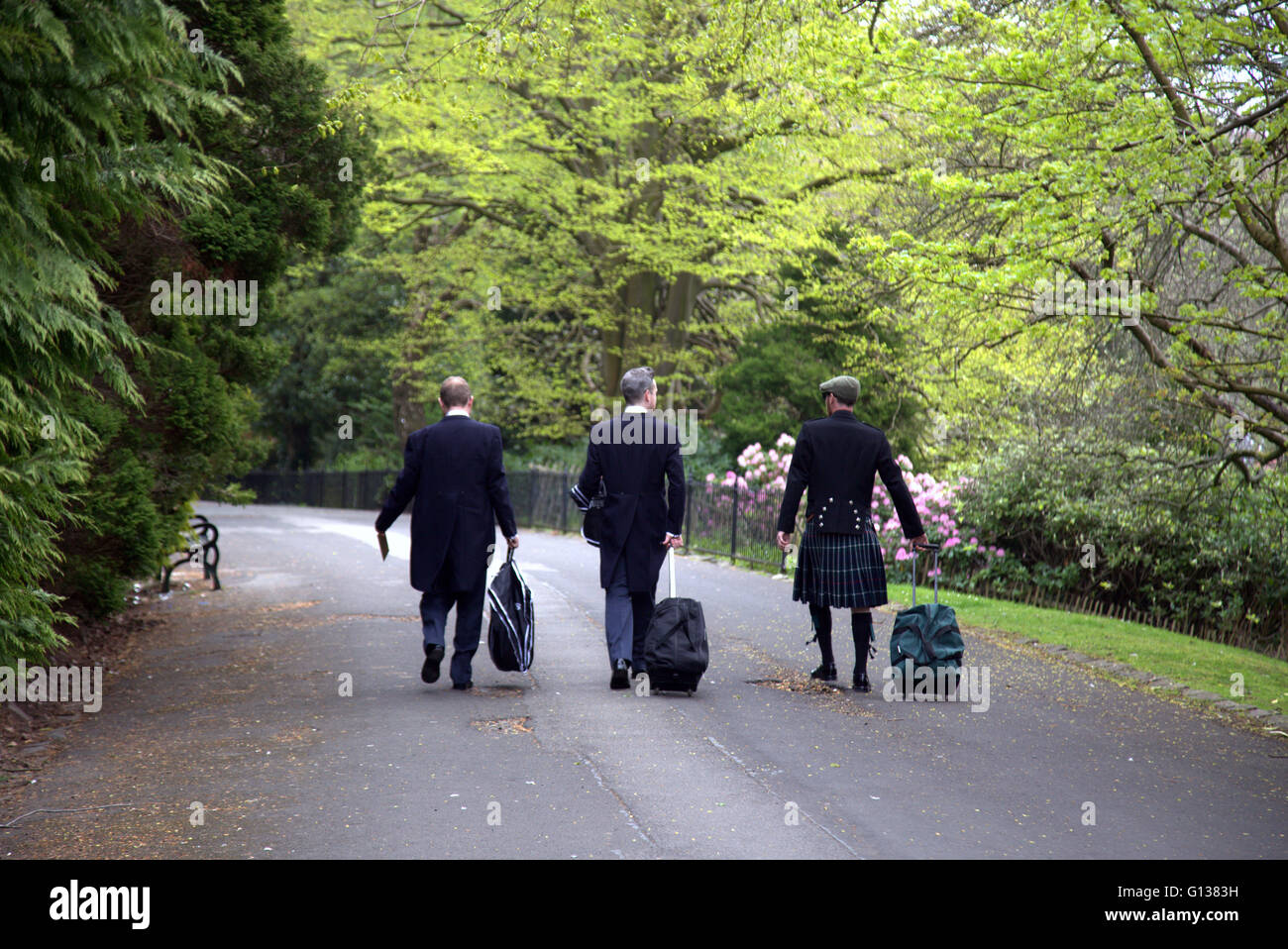 Drei Hochzeitsgäste auf der Straße im Kelvingrove Park Glasgow,Scotland,U.K passendes Gewand. Stockfoto