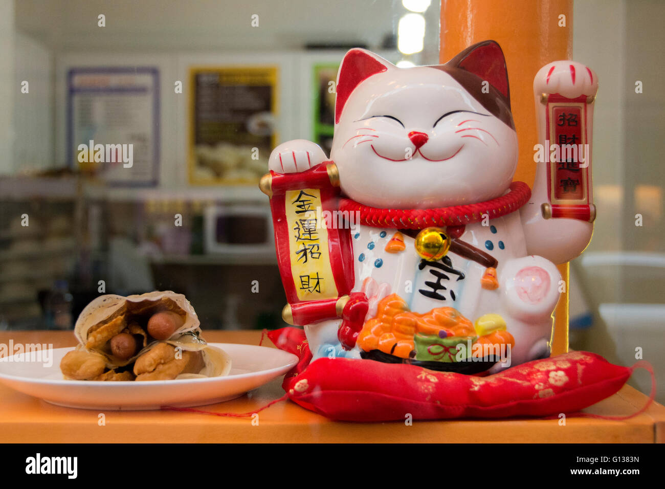 Maneki Neko (japanische verlockende Katze) in einem Restaurant Fenster in Soho, London, UK Stockfoto