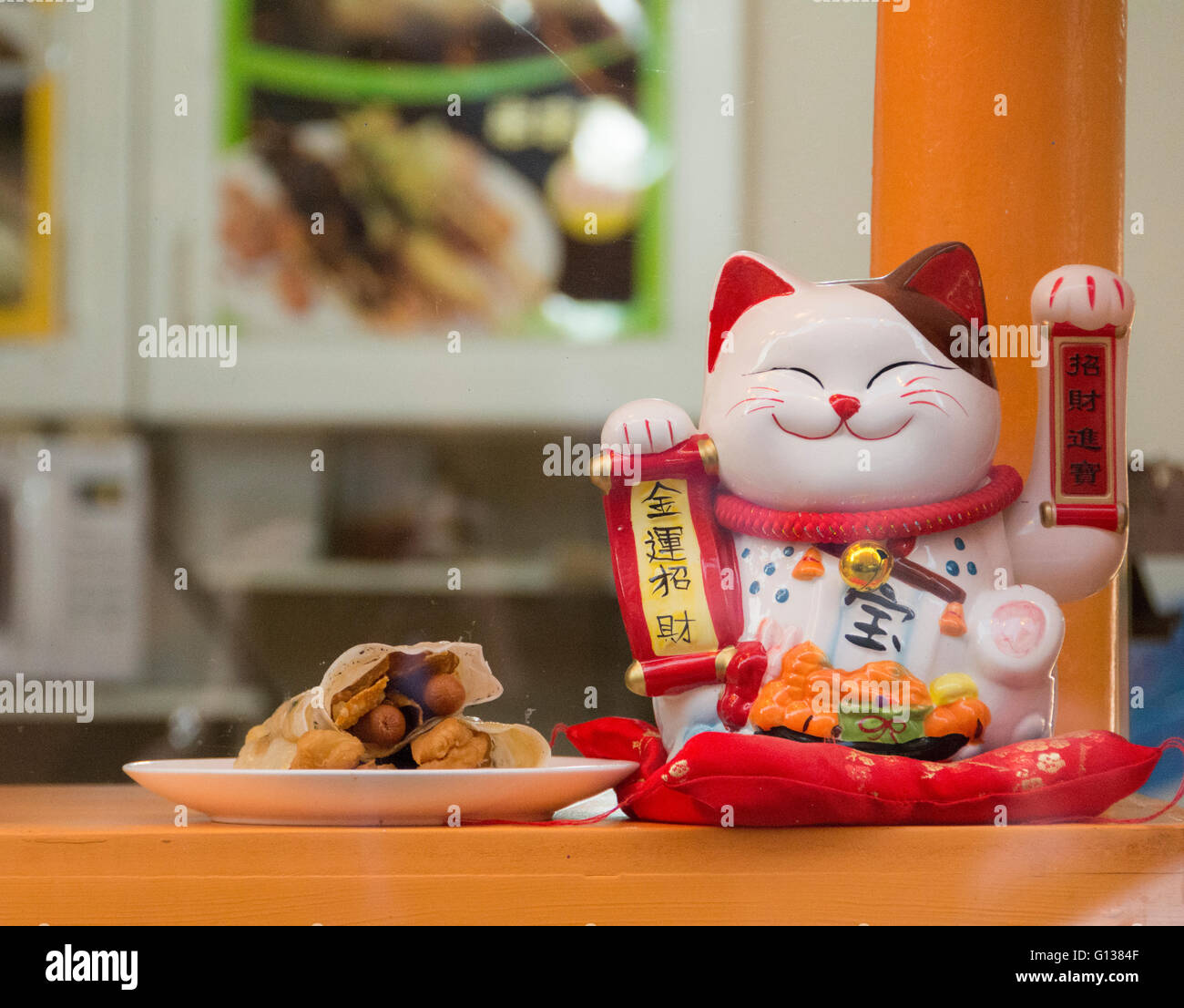 Maneki Neko (japanisch sprechende Katze) in einem Restaurantfenster in China Town, Soho, London, Großbritannien Stockfoto