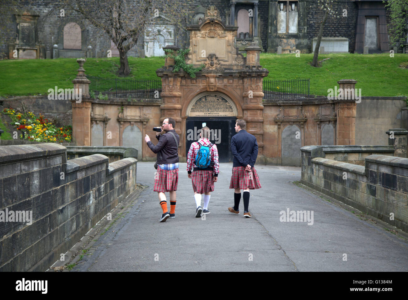 drei männliche Touristen Fuß über die Brücke der Seufzer sportlichen Tribut Kostüme in der Nekropole von Glasgow, Schottland, Großbritannien Stockfoto